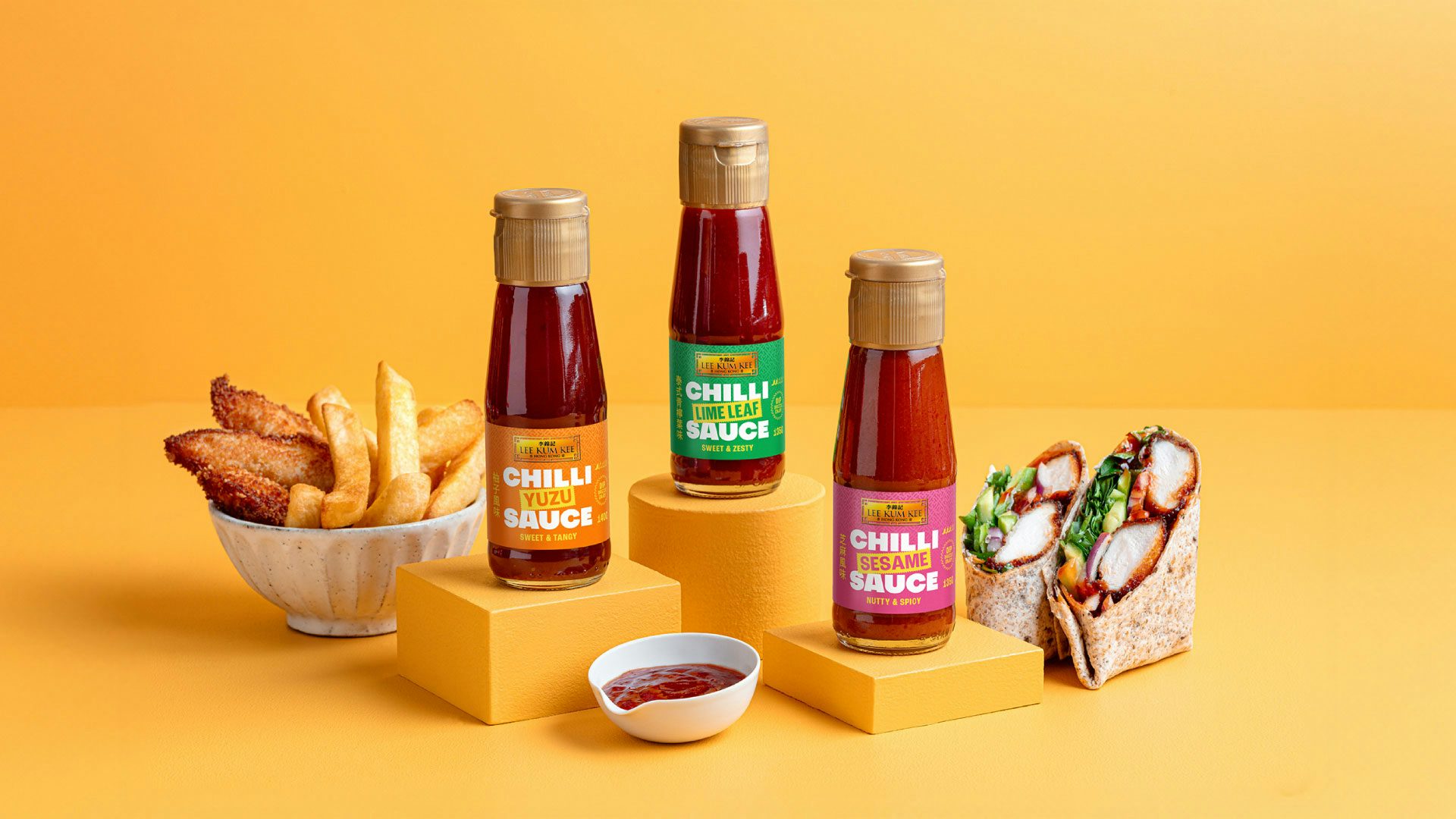 Lineup of three bottles of Lee Kum Kee chilli sauces shot alongside snacks and wraps
