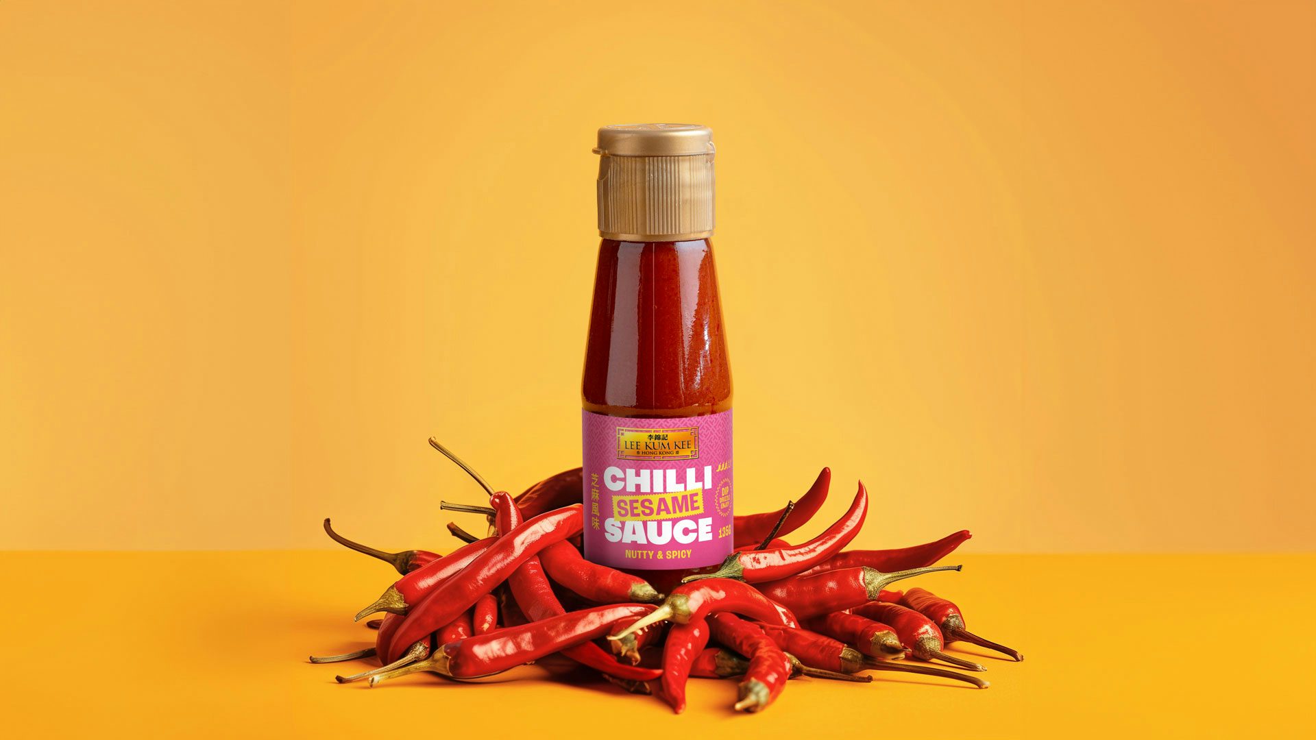 A bottle of Lee Kum Kee chilli sauce featuring a pink label, surrounded by a pile of chillies