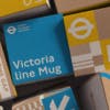 A pile of cube shaped packaging boxes in a palette of brown, blue and yellow, featuring London Transport Museum packaging