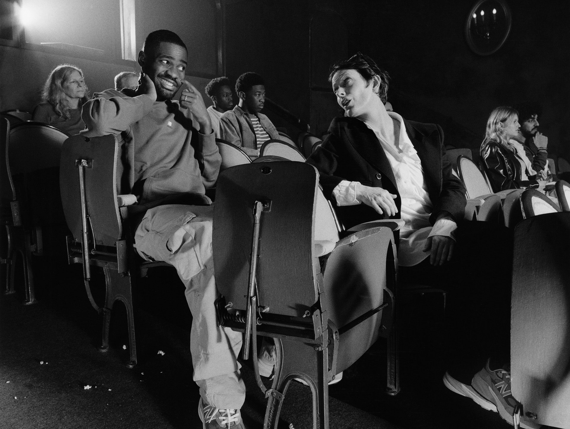 Black and white shot of British rapper Dave in a cinema pulling an awkward face